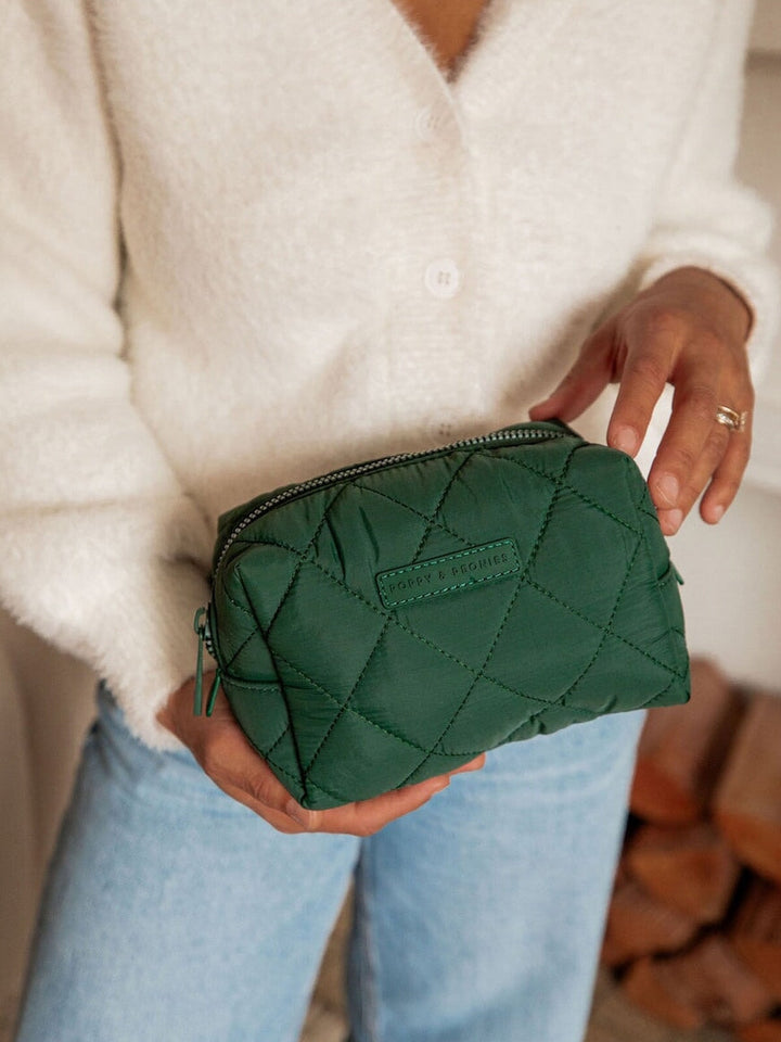 Person holding a green quilted makeup bag
