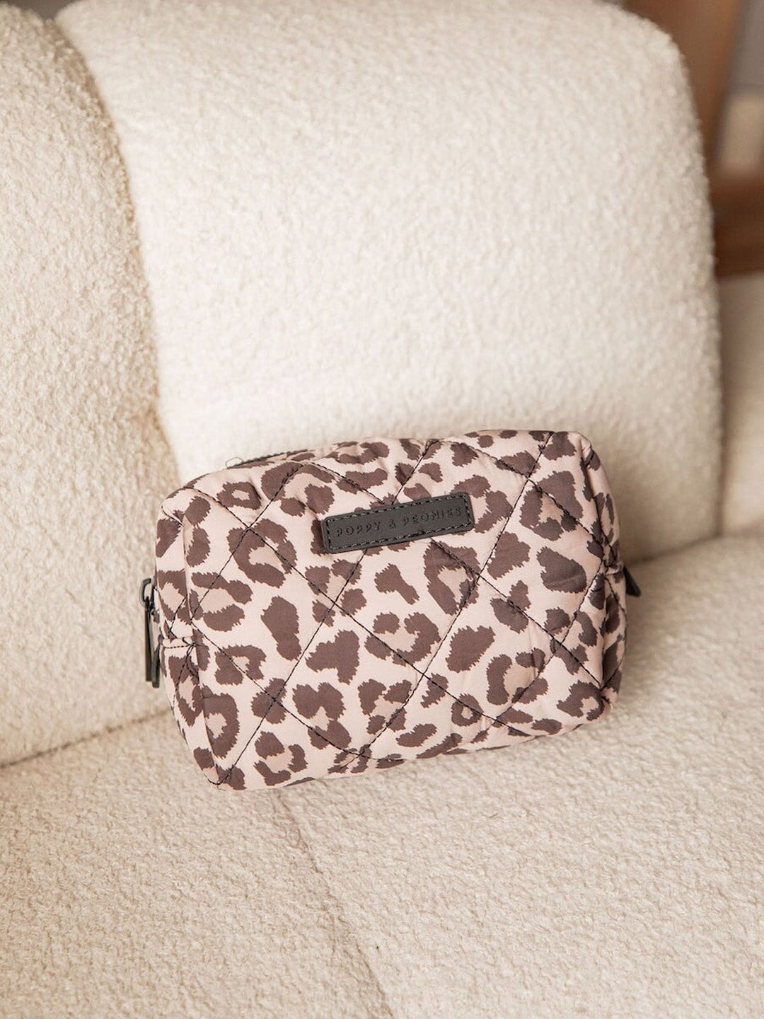Leopard print makeup bag on a beige couch
