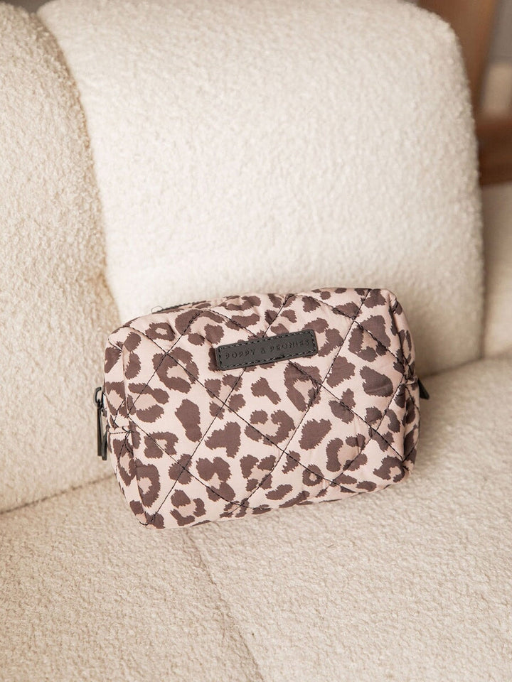 Leopard print makeup bag on a beige couch