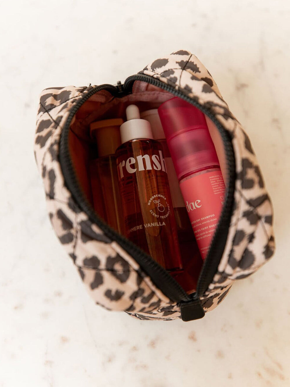 Quilted leopard print makeup bag with skincare products on a light background