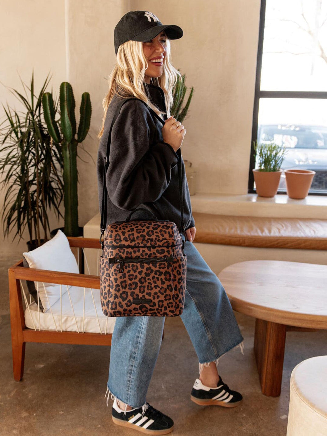 Person wearing a leopard print lunch bag on their shoulder in an indoor setting