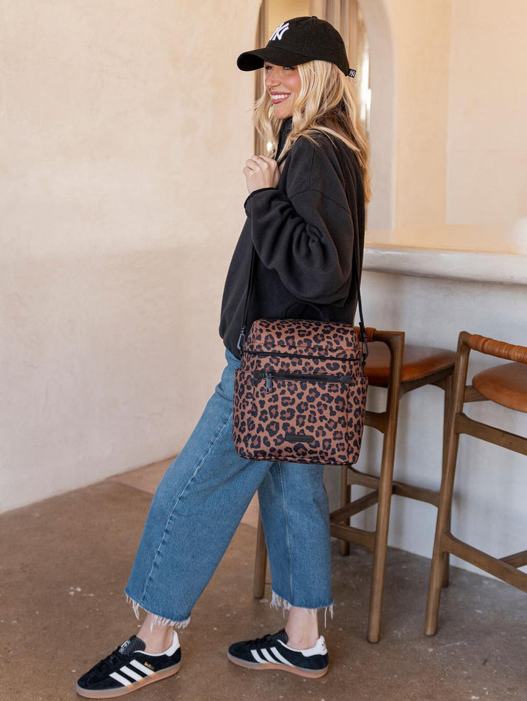 Woman holding a leopard print lunch bag in an indoor setting