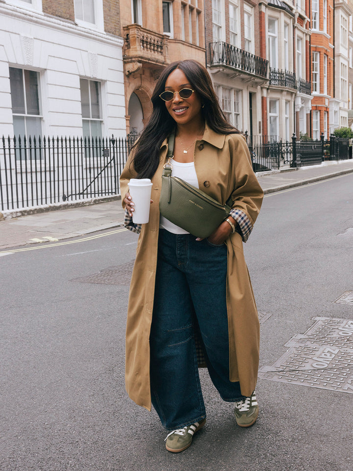 Woman walking with the Poppy & Peonies The Sidekick in Olive worn as a crossbody while holding a takeaway cup.