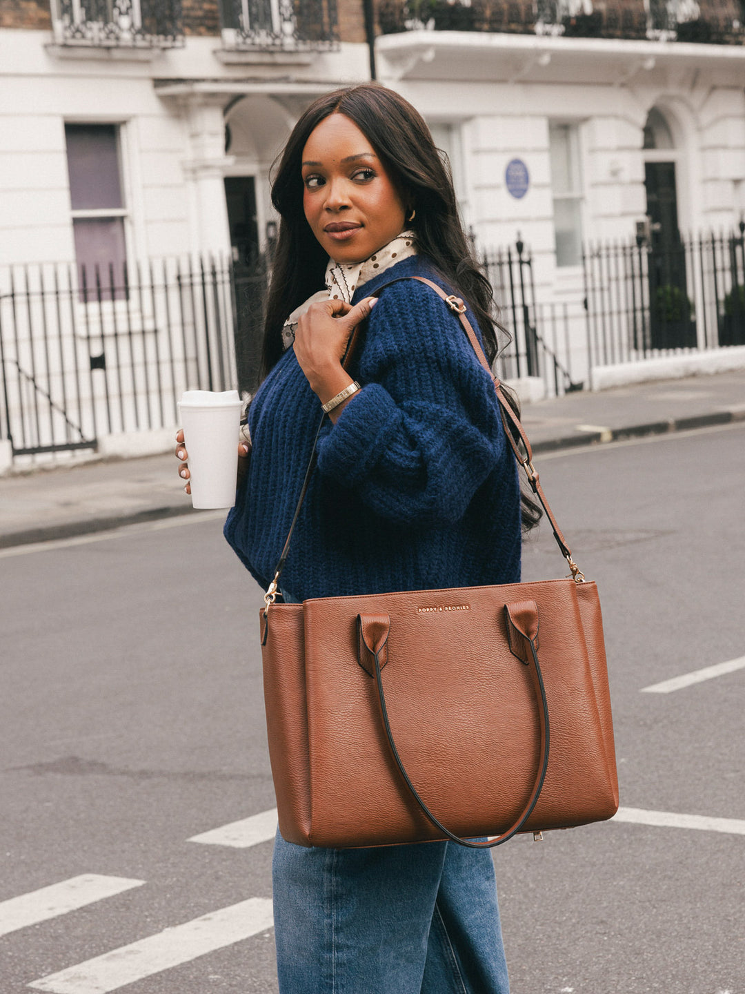Woman carrying the Poppy & Peonies Double Duty Tote in Chestnut with the removable crossbody strap while holding a takeaway coffee.