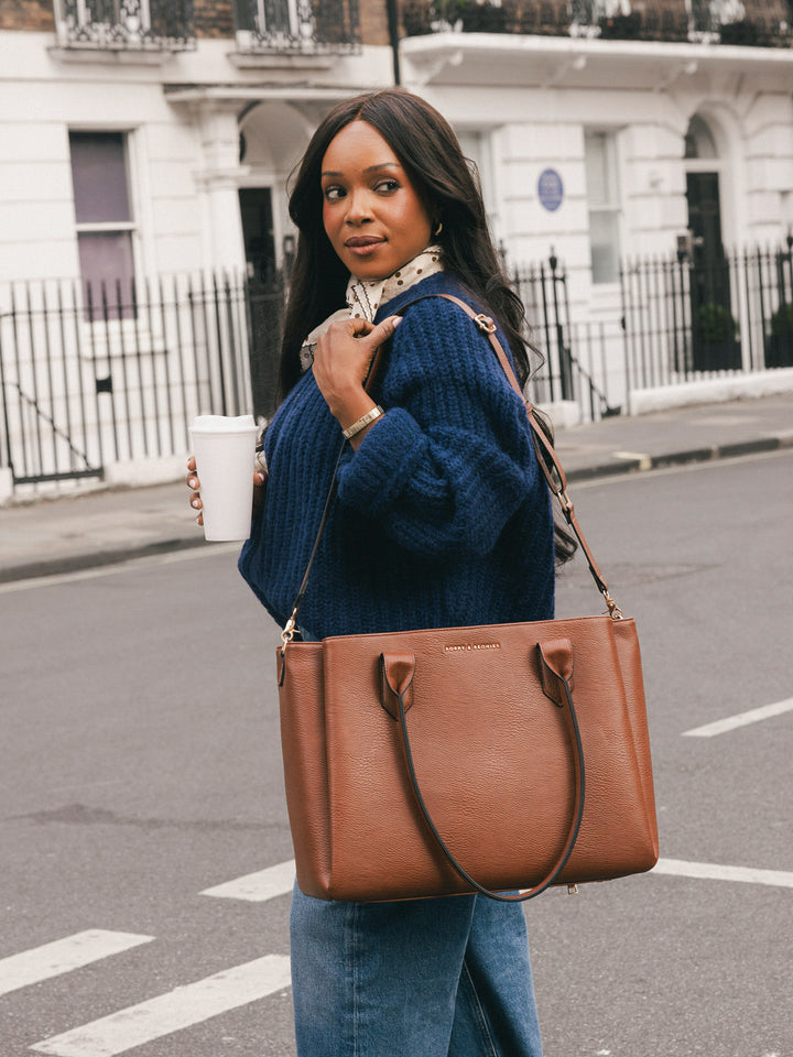 Woman carrying the Poppy & Peonies Double Duty Tote in Chestnut with the removable crossbody strap while holding a takeaway coffee.