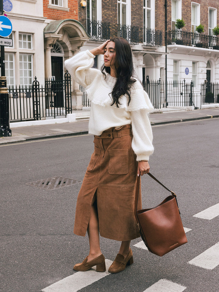 Woman walking with the Poppy & Peonies The Bucket Bag in Chestnut carried by the shoulder strap on a London street.