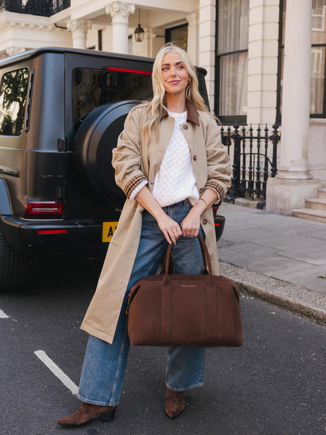 Poppy & Peonies Take Off Tote in Espresso Suede carried by the top handles outdoors, showcasing its spacious structured shape and soft suede finish.