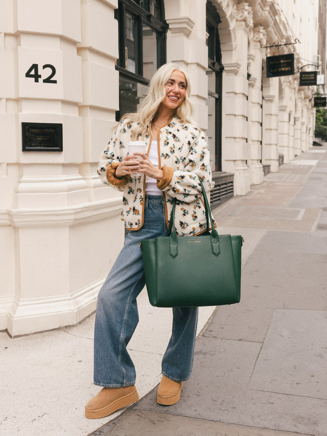 Woman carrying the Poppy & Peonies Double Duty Tote in Heritage Green by the top handles while walking through the city.