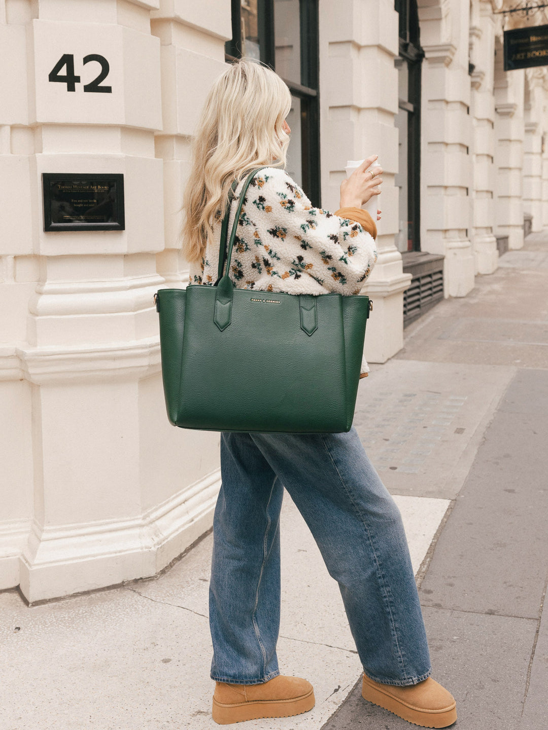 Side view of a woman carrying the Poppy & Peonies Double Duty Tote in Heritage Green over the shoulder with the top handles.