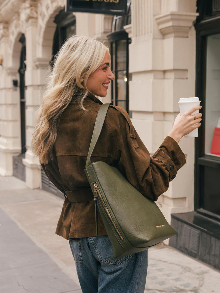Lifestyle shot of a woman wearing the Poppy & Peonies Bucket Bag in Olive over the shoulder, highlighting the structured silhouette and shoulder strap.