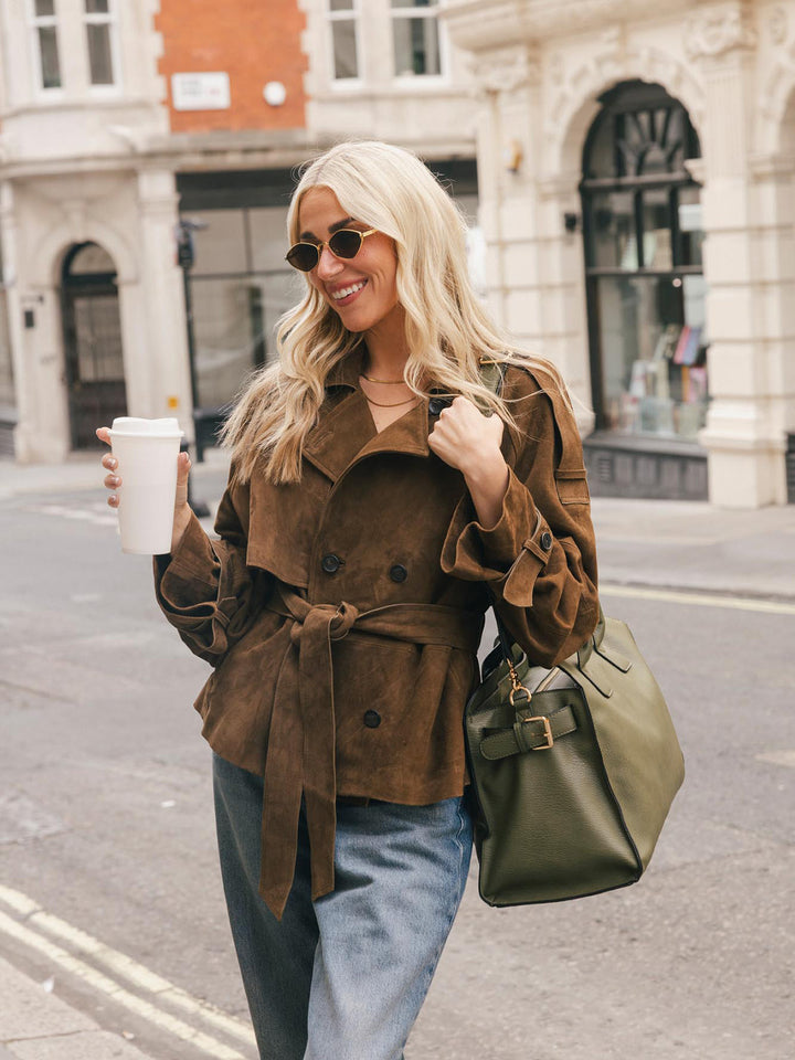 Lifestyle shot of a woman carrying the Poppy & Peonies Uptown Tote in Olive over her shoulder while holding a takeaway coffee.