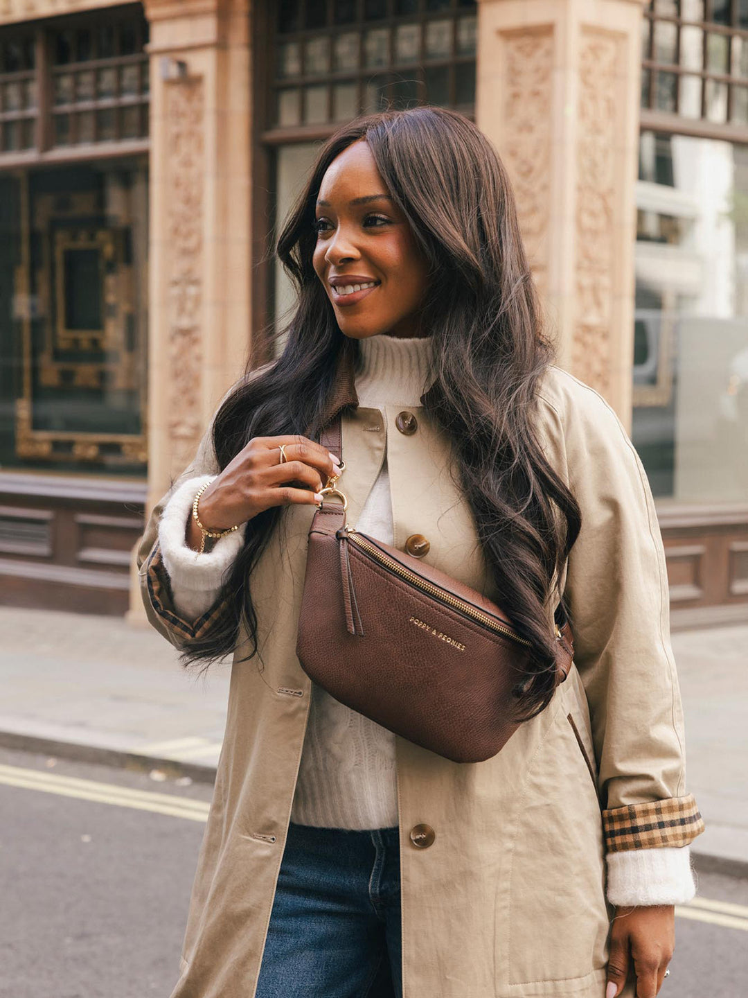 Close-up lifestyle shot of a woman wearing the Poppy & Peonies Sidekick in Espresso crossbody, highlighting the front zipper and compact silhouette.