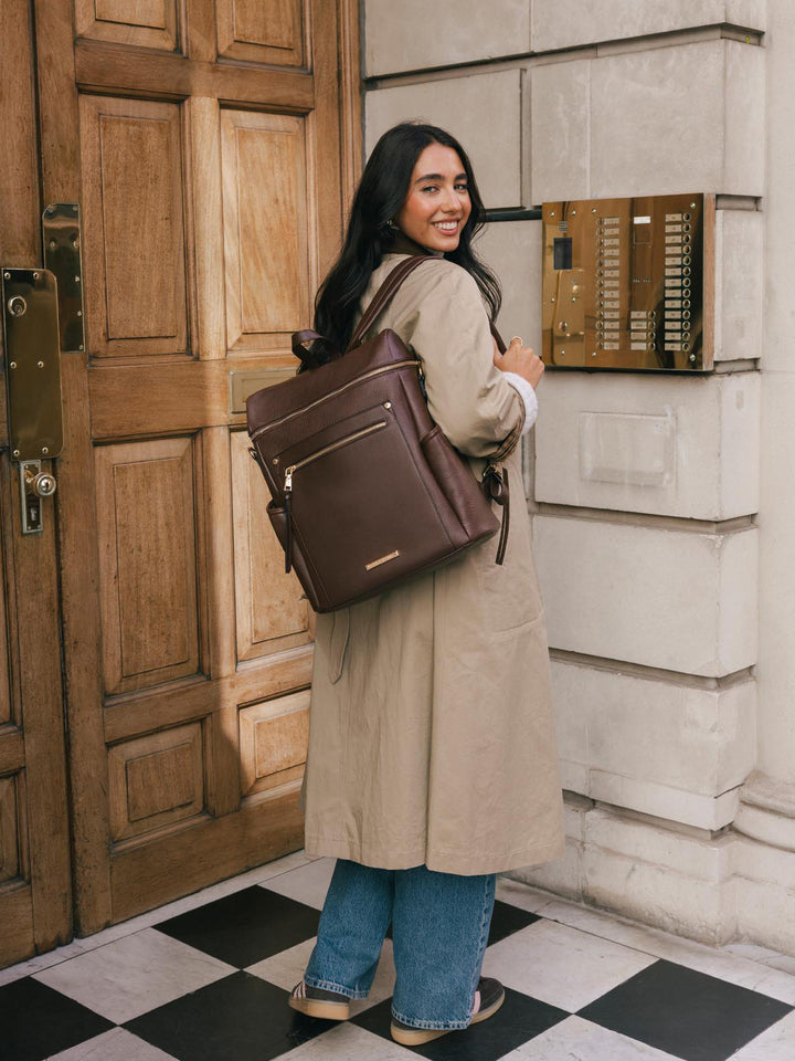 Woman looking back while wearing the Poppy & Peonies Commuter Backpack in Espresso over both shoulders.