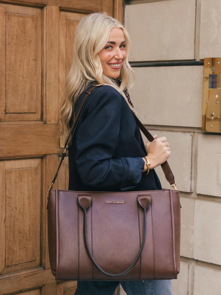 Woman smiling while carrying the Poppy & Peonies Multitasker in Espresso over her shoulder.
