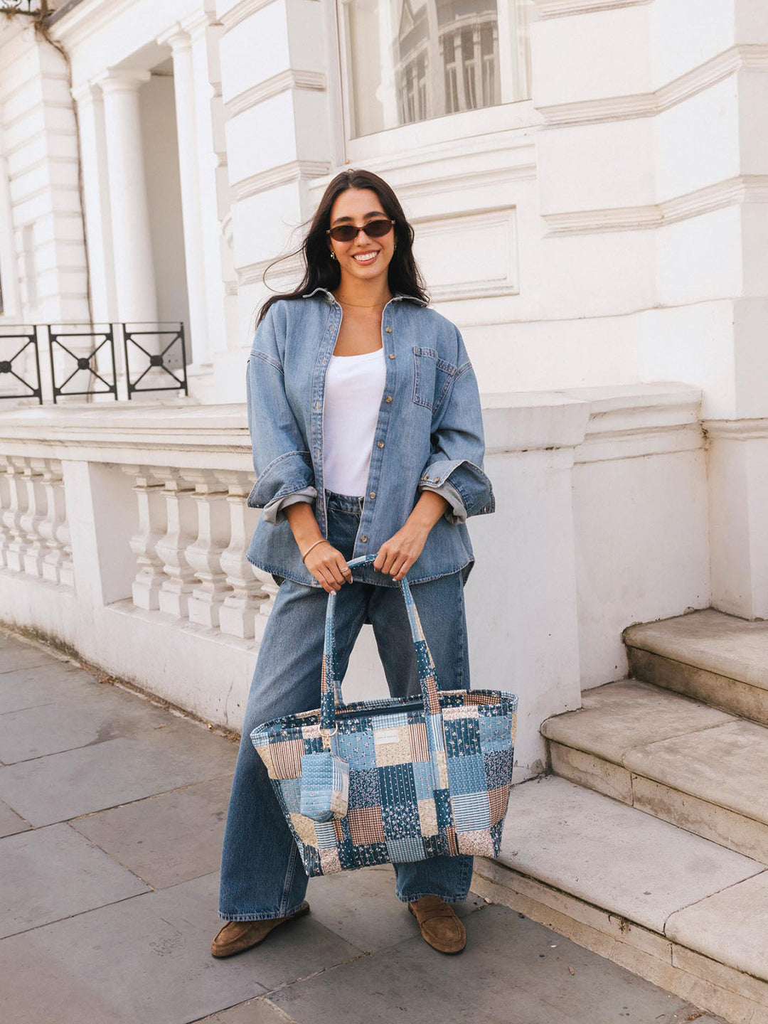 Woman posing with the Poppy & Peonies Daydreamer Tote in Navy Patchwork carried by the top handles.