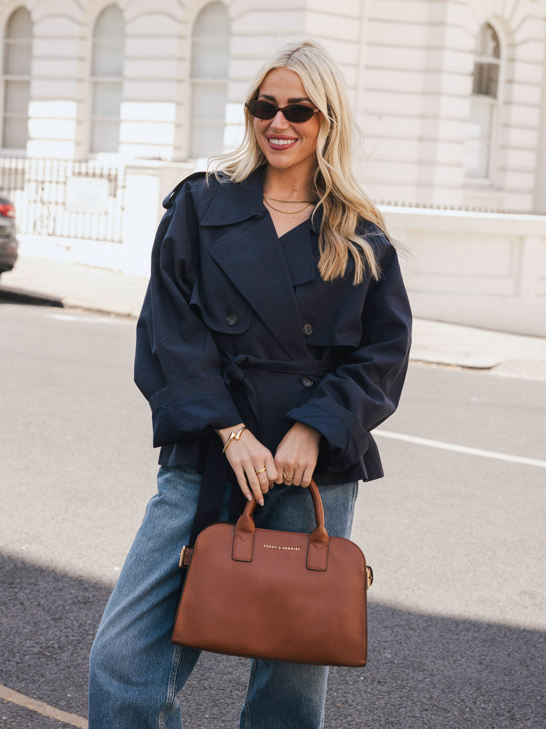 Woman holding the Poppy & Peonies Mini Uptown Tote in Chestnut by the top handles while smiling outdoors.