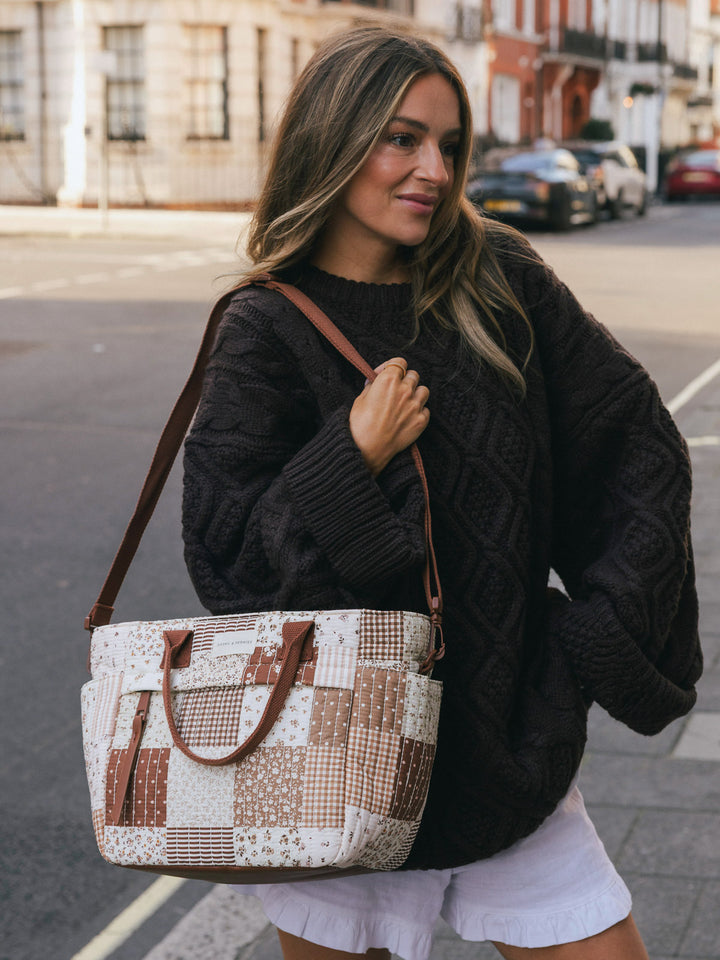 Woman carrying the Poppy & Peonies New Lunch Bag in Brown Patchwork over her shoulder while posing on a city street.