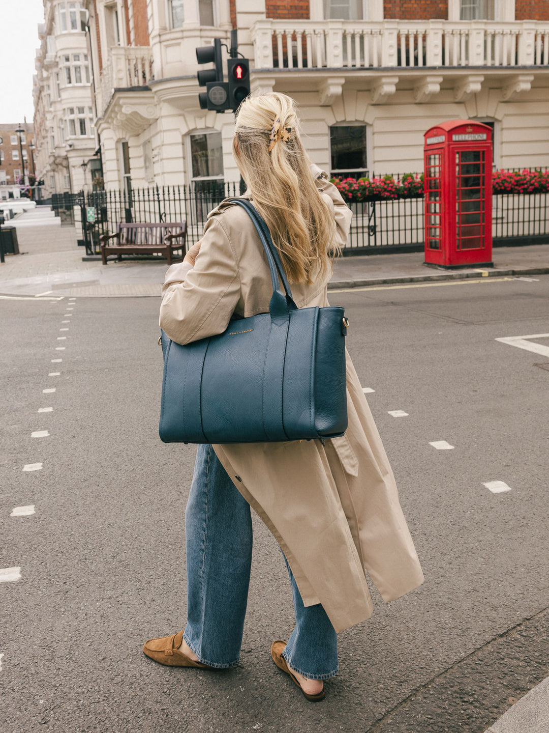 Woman carrying the Poppy & Peonies Multitasker in Navy over her shoulder while walking on a city street.