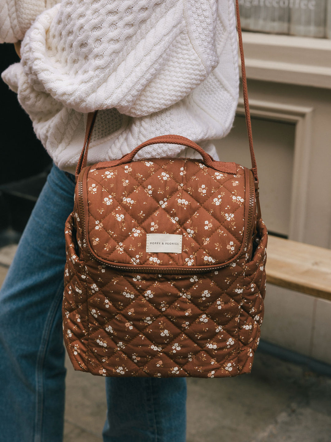 Close-up product-focused shot of the Poppy & Peonies Lunch Date in Brown Floral worn over the shoulder, highlighting the quilted floral print and front flap.
