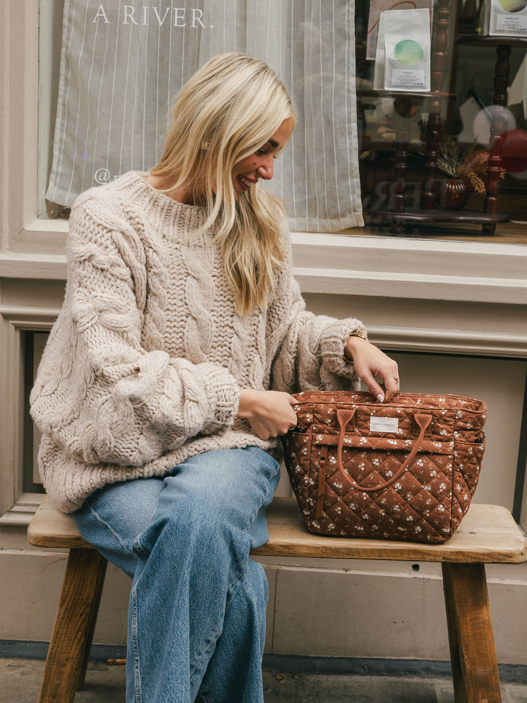 Seated lifestyle shot of a woman interacting with the Basic Lunch Bag in Brown Floral beside her.