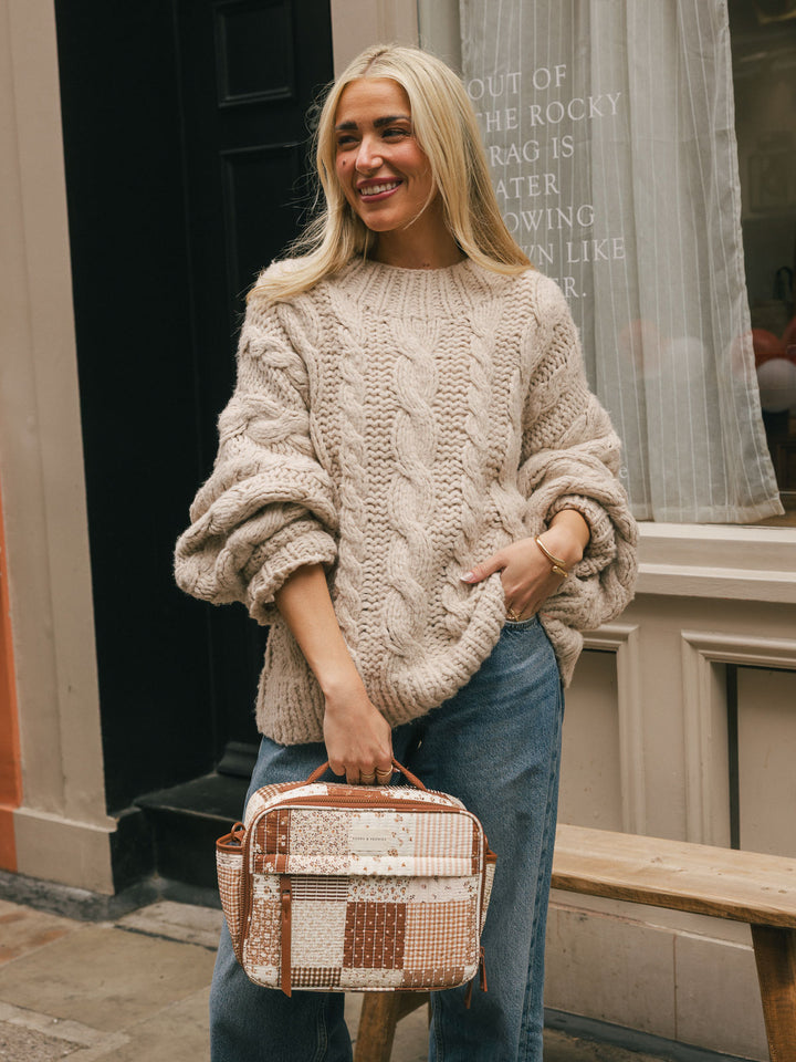 Lifestyle shot of a woman holding the Poppy & Peonies Basic Lunch Bag in Brown Patchwork by its top handle.