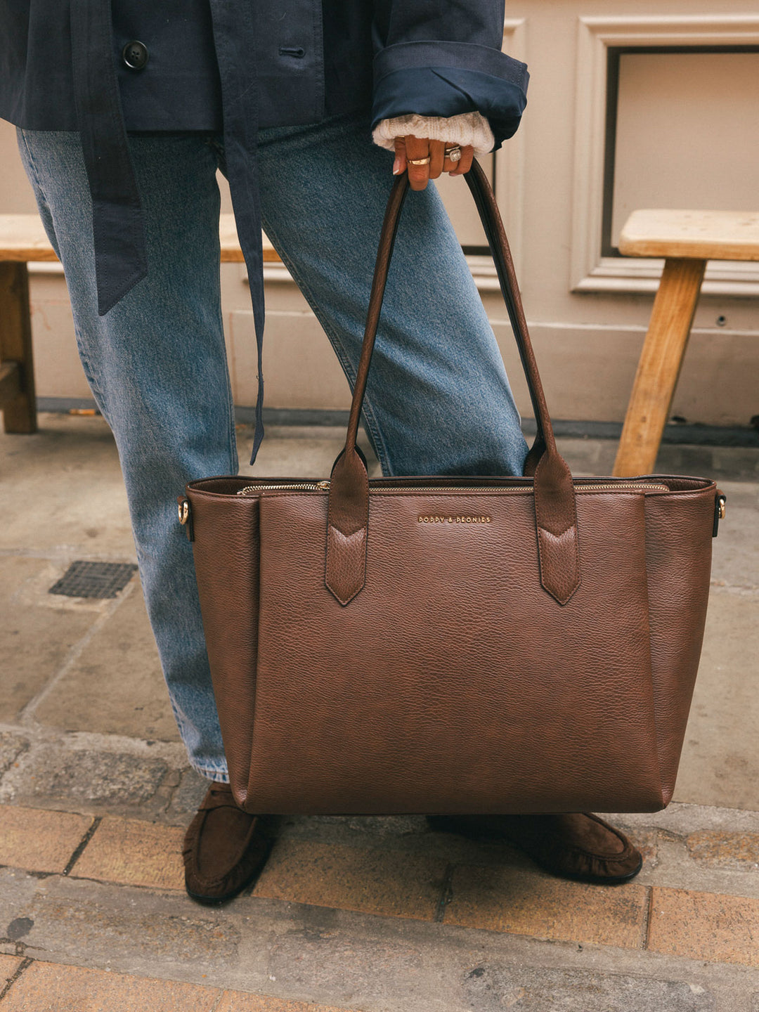 Close-up of a woman carrying the Poppy & Peonies Double Duty Tote in Espresso by the top handles over her shoulder.