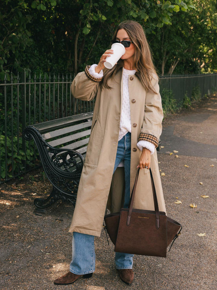 Poppy & Peonies Mini Avenue Tote in Espresso Suede carried by hand while enjoying coffee in the park, highlighting its compact silhouette and suede exterior.