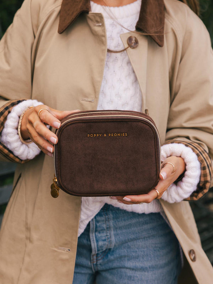 Poppy & Peonies Pretty Connected Case in Espresso Suede held in hand outdoors, showing its compact size, structured shape and gold-tone logo.