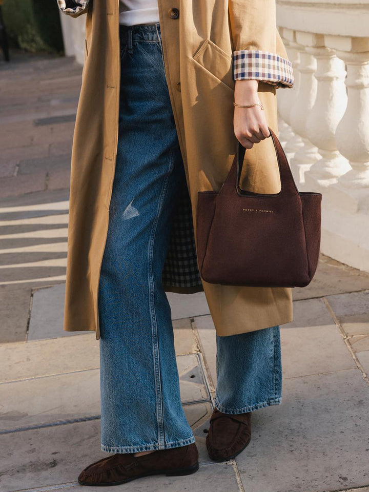 Close-up of Poppy & Peonies The Pick Me Up Tote in Espresso Suede carried by the top handles, highlighting the rich suede texture and structured silhouette.