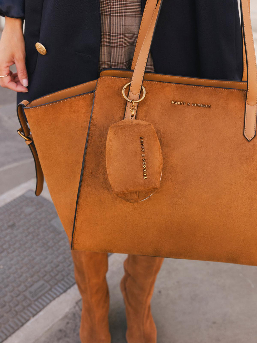Close-up of Poppy & Peonies Avenue Tote in Cognac Suede, highlighting the soft suede exterior, smooth vegan leather straps and coordinating Tag Along in Cognac Suede bag charm.