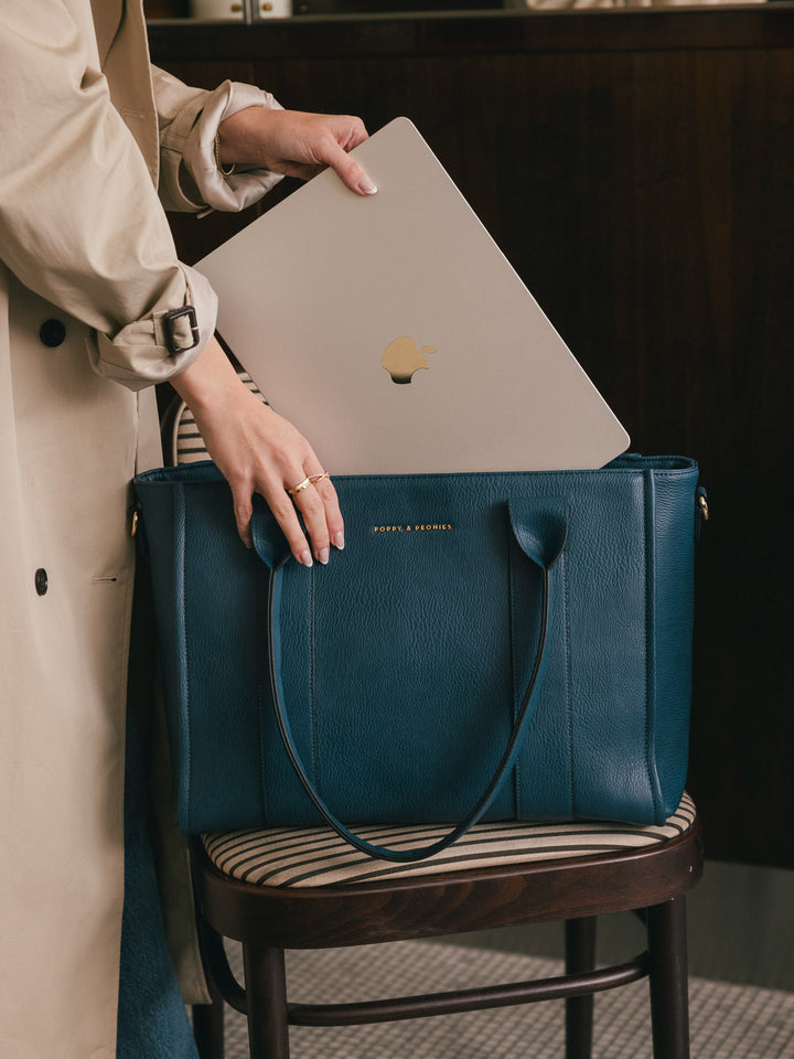 Close-up product-focused shot of a laptop being placed inside the Poppy & Peonies Multitasker in Navy, highlighting its spacious interior.