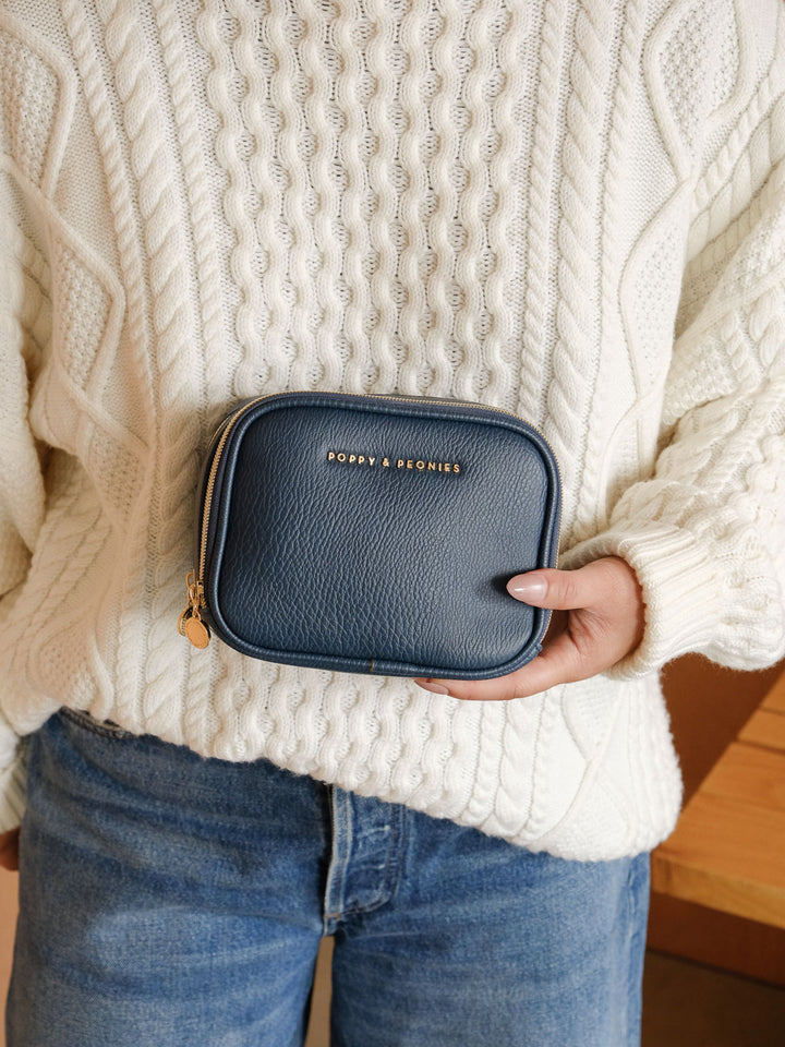 Close-up lifestyle shot of a woman holding the Poppy & Peonies Split Organizer in Navy, showcasing its structured silhouette, textured finish and zip-around closure.