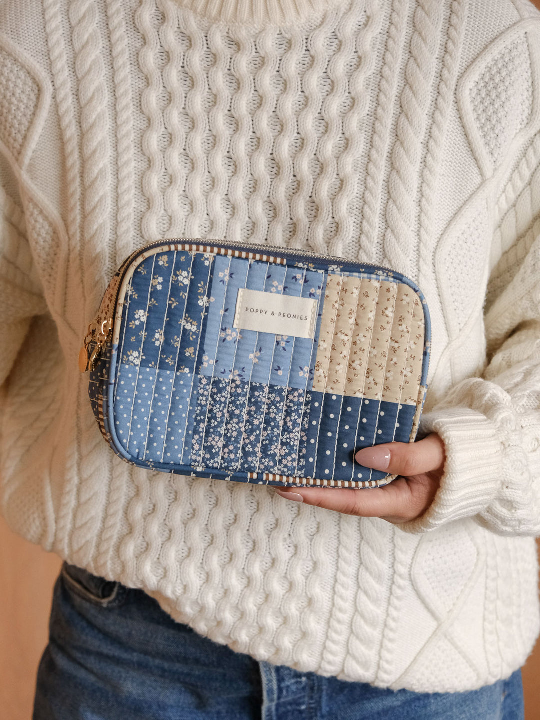 Product-focused lifestyle shot of a woman holding the Poppy & Peonies Split Organizer in Navy Patchwork, highlighting its quilted patchwork design and zip-around closure.