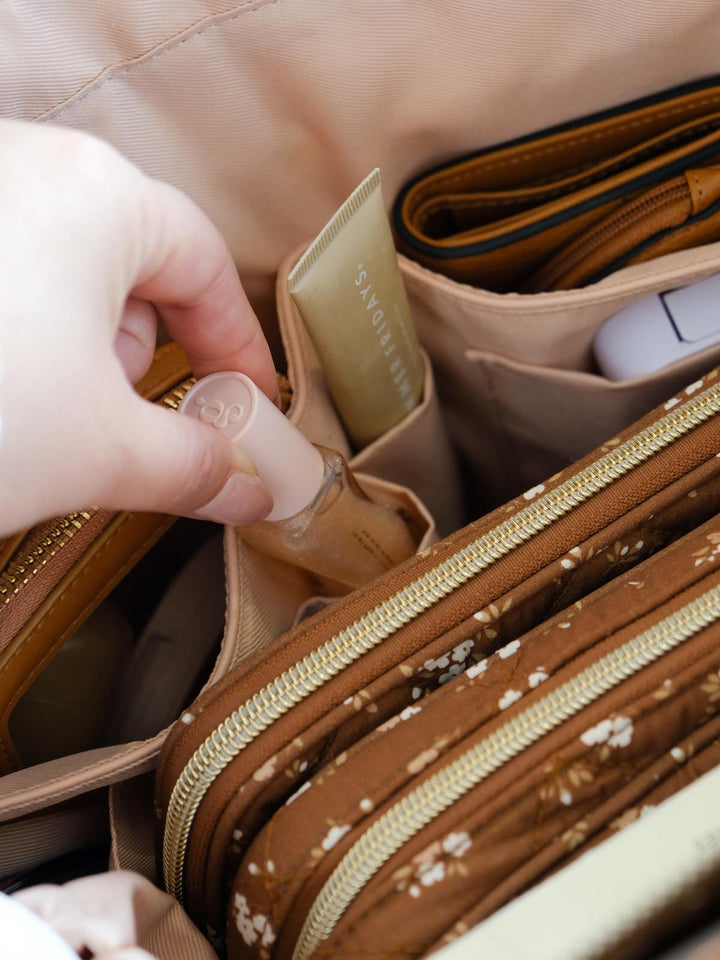 Close-up of the Daydreamer Tote in Brown Floral highlighting its interior organization with dedicated pockets holding beauty products, a wallet, and small everyday essentials.