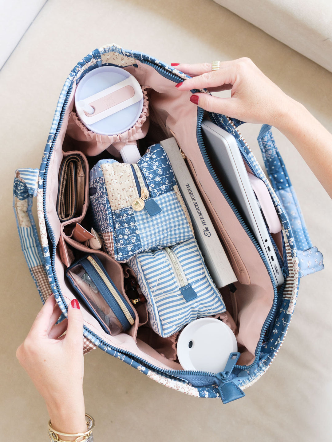 Overhead lifestyle shot of the Daydreamer Tote in Navy Patchwork showing its spacious interior filled with a laptop, pouches, wallet, and everyday essentials.