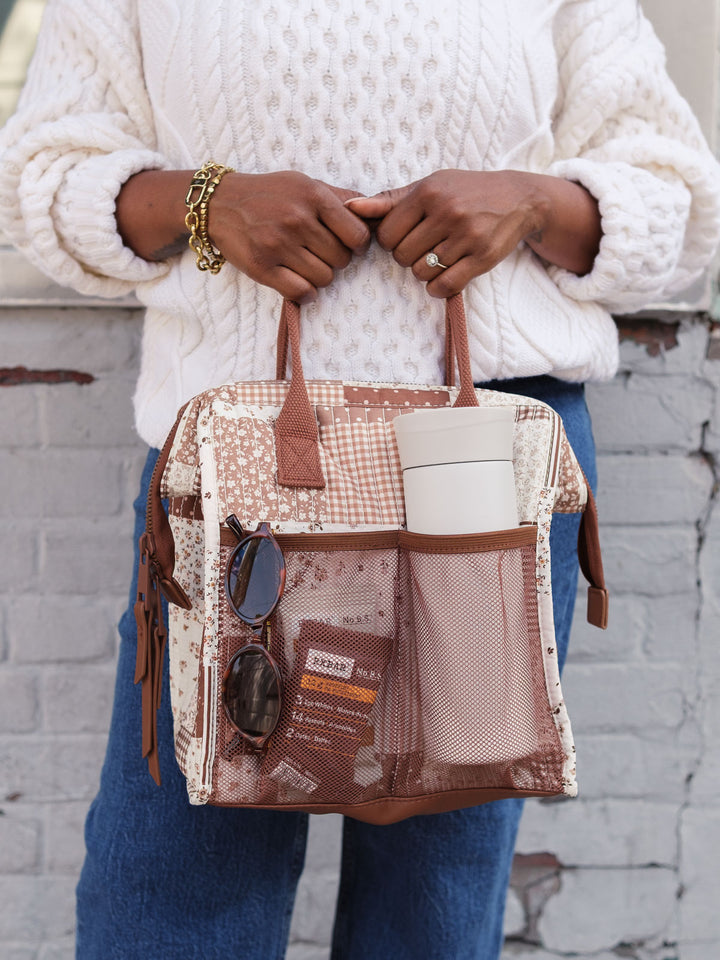 Close-up lifestyle shot of the Poppy & Peonies The Lunch Bag in Brown Patchwork with the front pocket packed with everyday essentials, highlighting its convenient exterior storage.