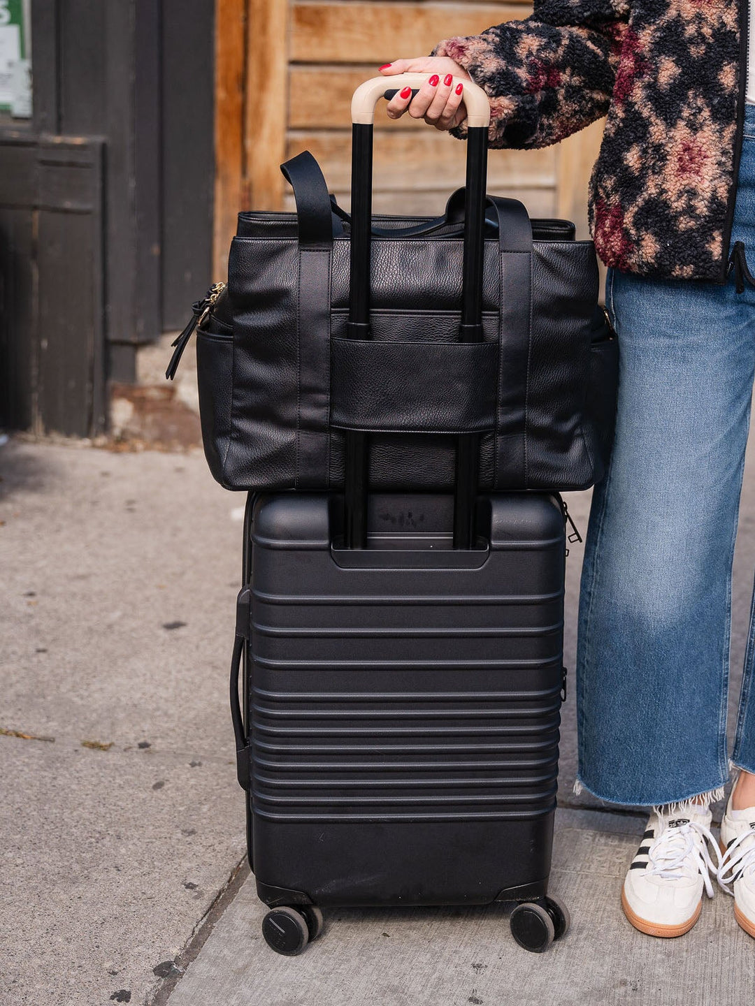 Close-up of the Poppy & Peonies Mini Voyager in Black secured over the handle of a rolling suitcase.