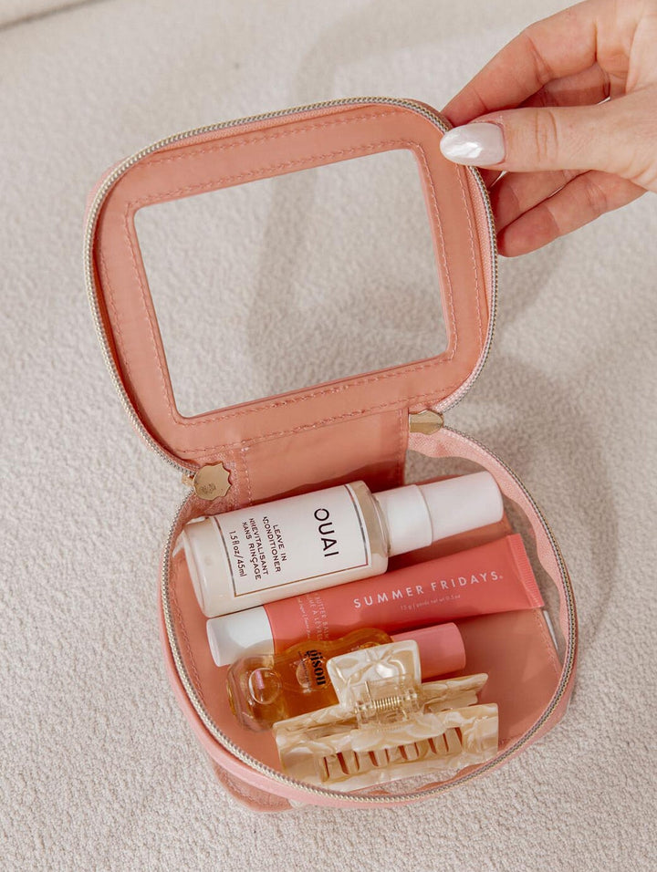 Pink travel case with OUAI and Summer Fridays products on a light background