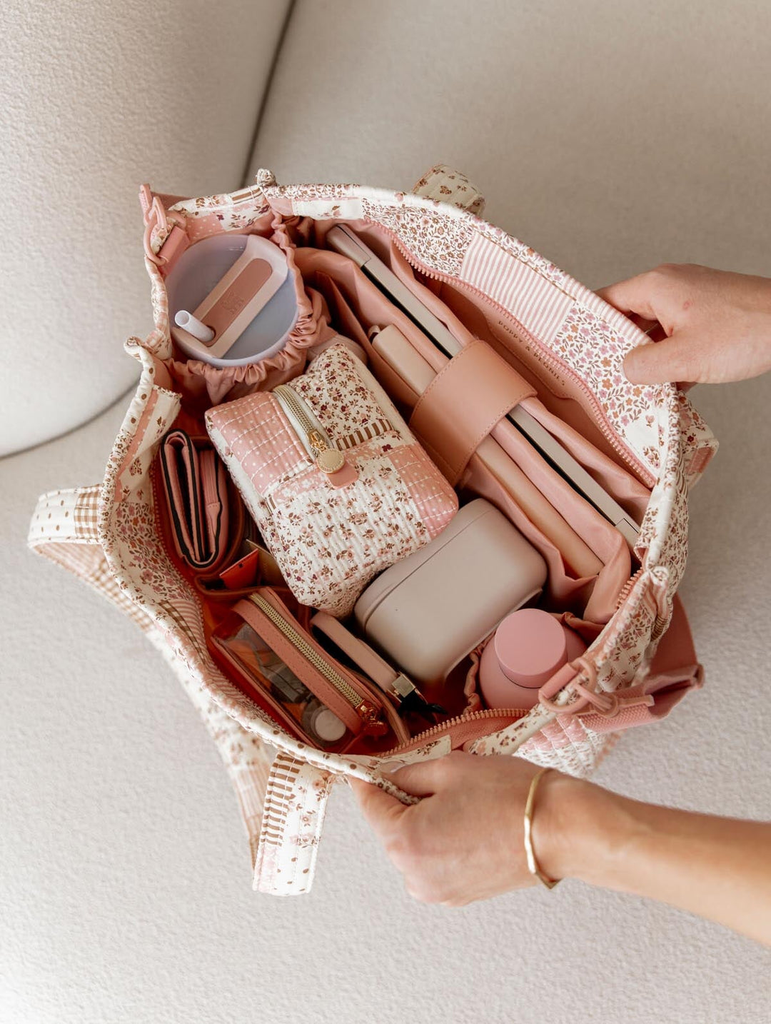 Open patchwork handbag containing with various items on a light background