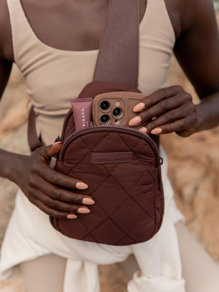 Person holding a brown quilted crossbody bag