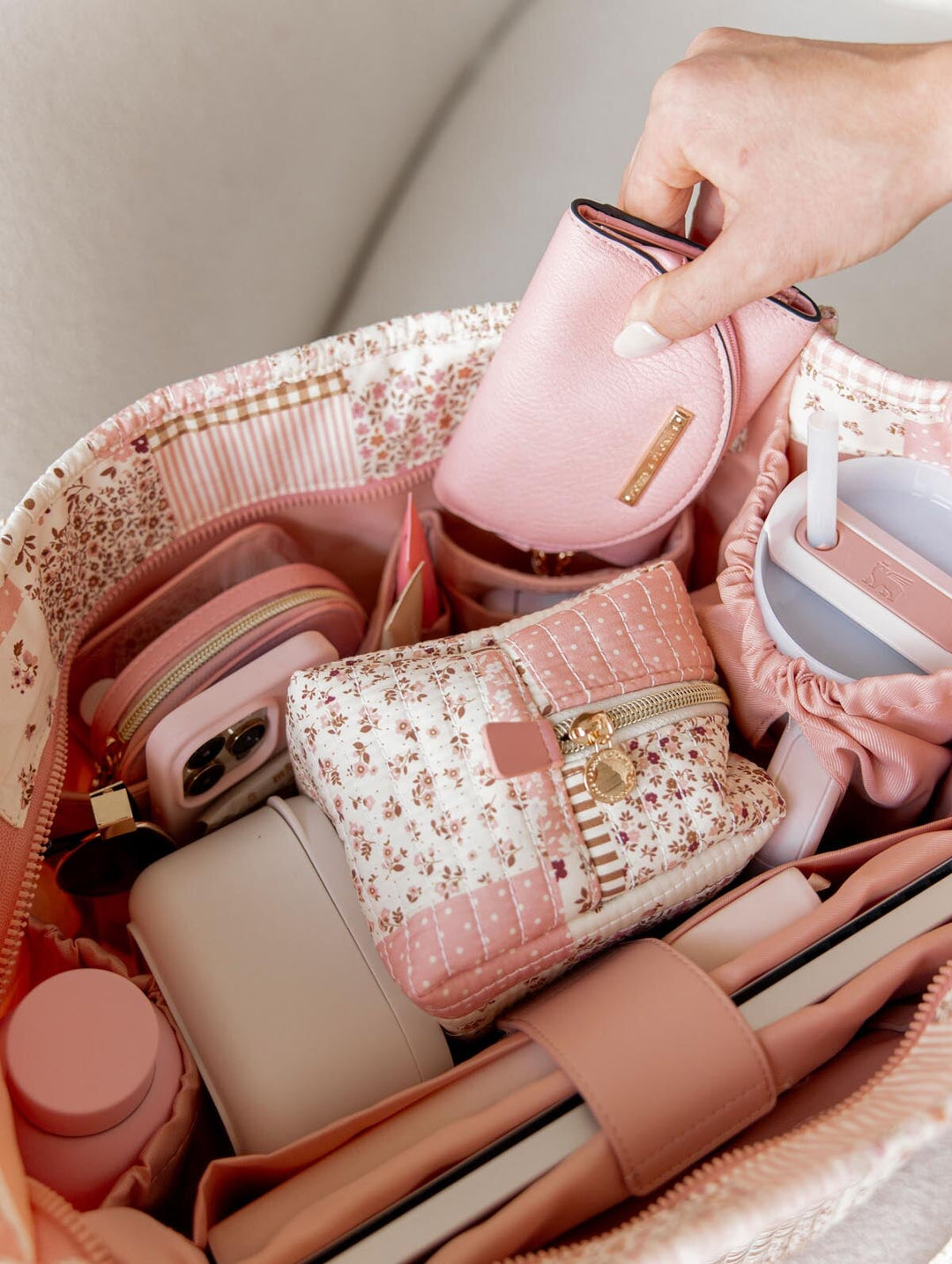 Hand pulling a pink wallet out of a patchwork tote bag