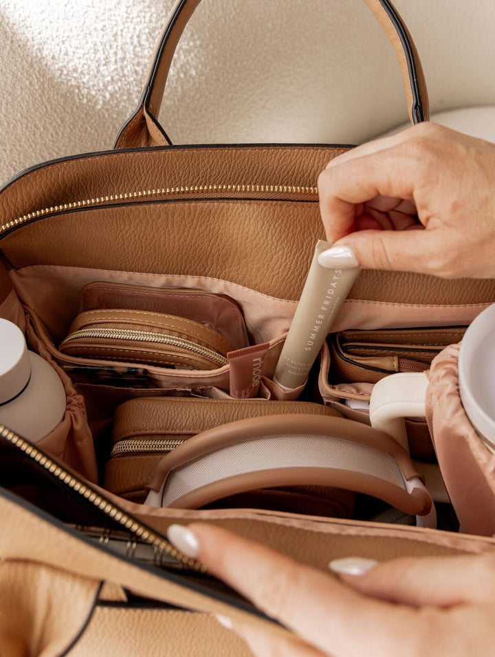 Hand pulling a lip balm out of a tote bag