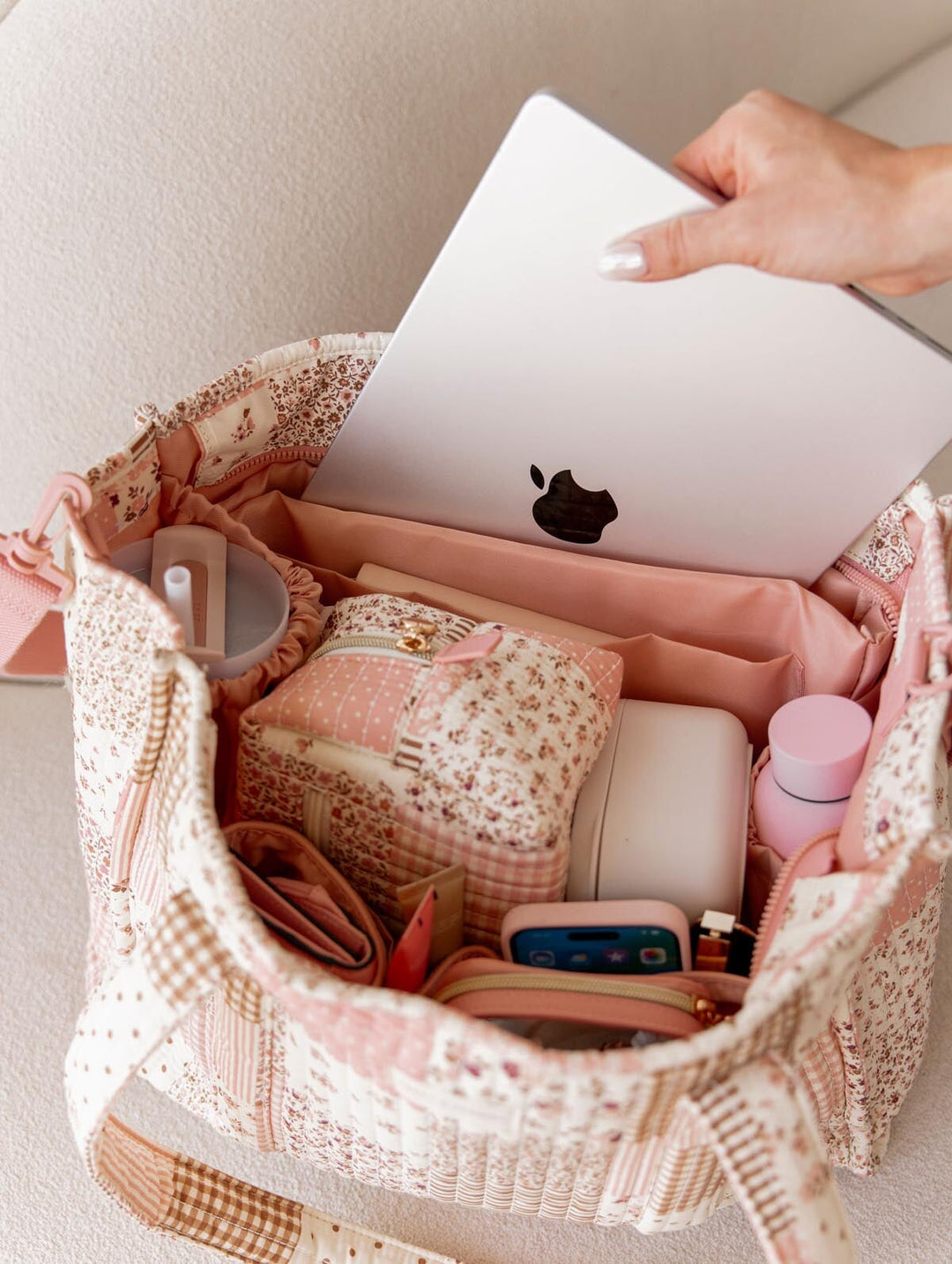 Hand pulling laptop out of a patchwork tote bag