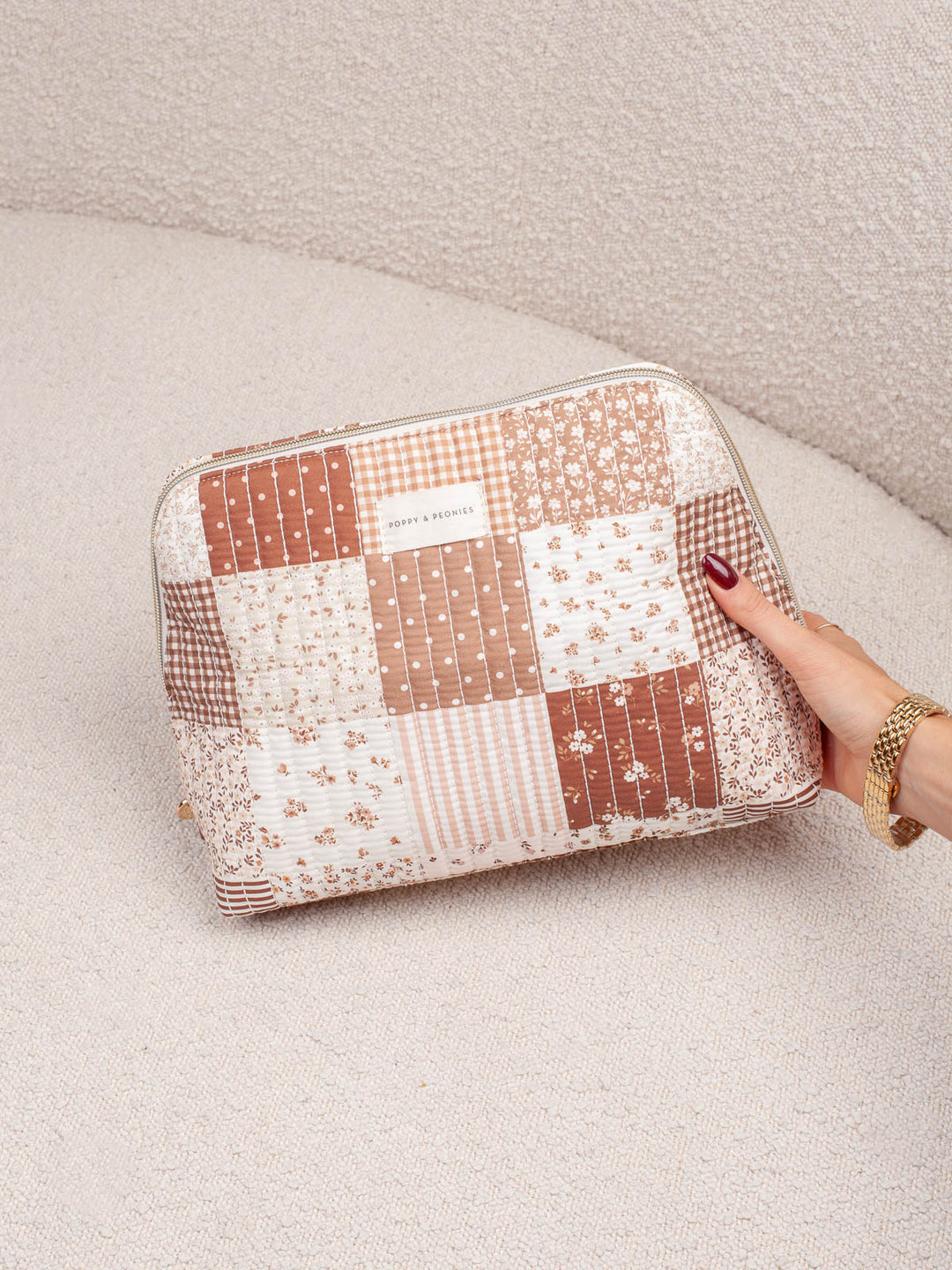 Poppy & Peonies Sitting Pretty Cosmetic Case in Brown Patchwork held by hand.