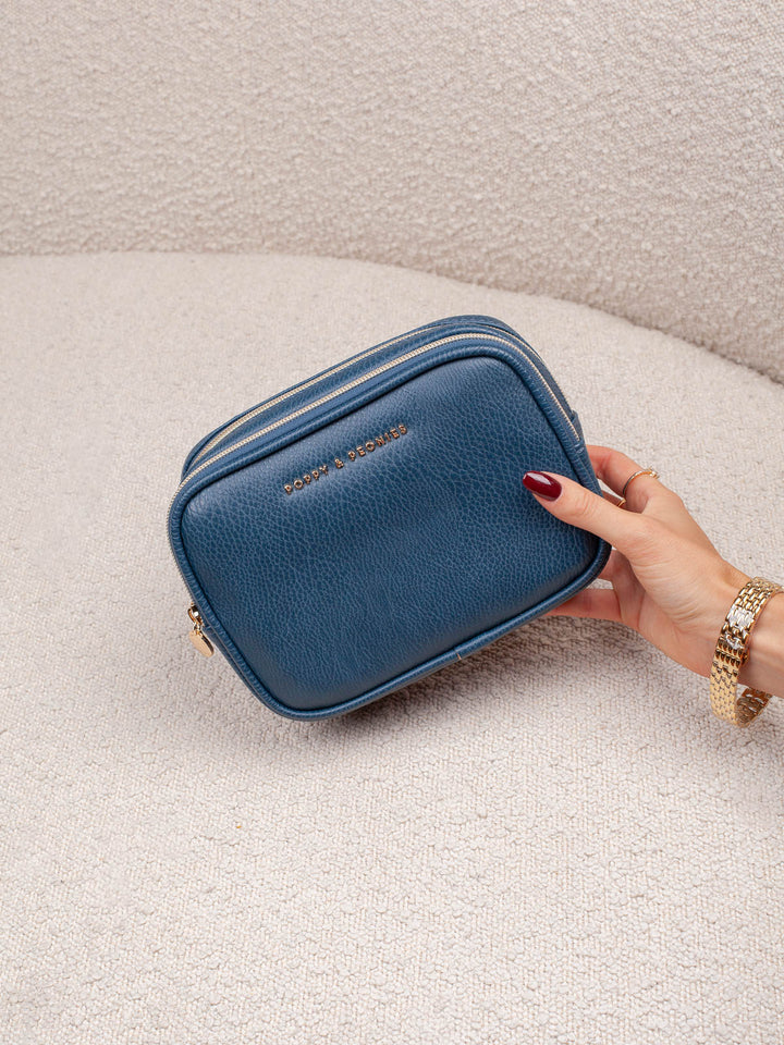 Product-focused lifestyle shot of The Split Organizer in Navy, highlighting its compact rectangular shape, rich navy finish, and zip-around closure.