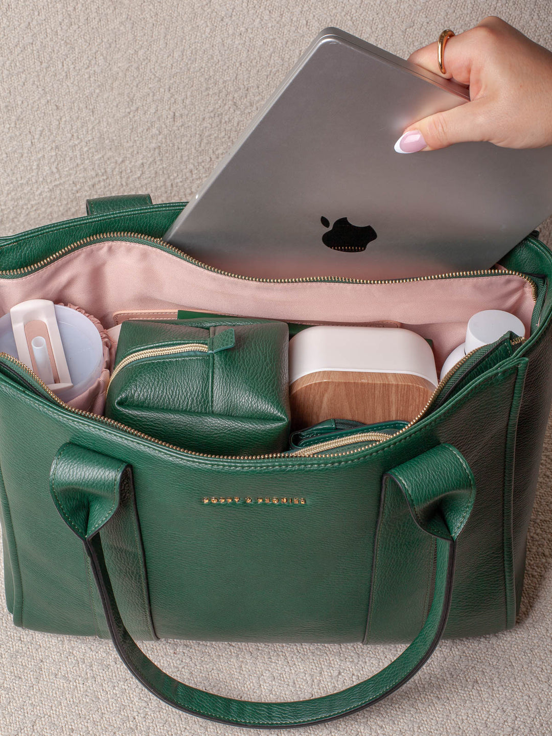 Lifestyle image of the Small Heritage in Green, showing the spacious main compartment with room for a laptop, cosmetic cases, and other daily essentials.