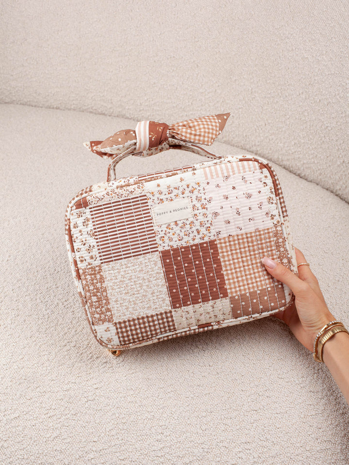 Product-focused lifestyle shot of the Small Hook Me Up in Brown Patchwork, showcasing the mixed patchwork prints, quilted construction, and bow handle. 