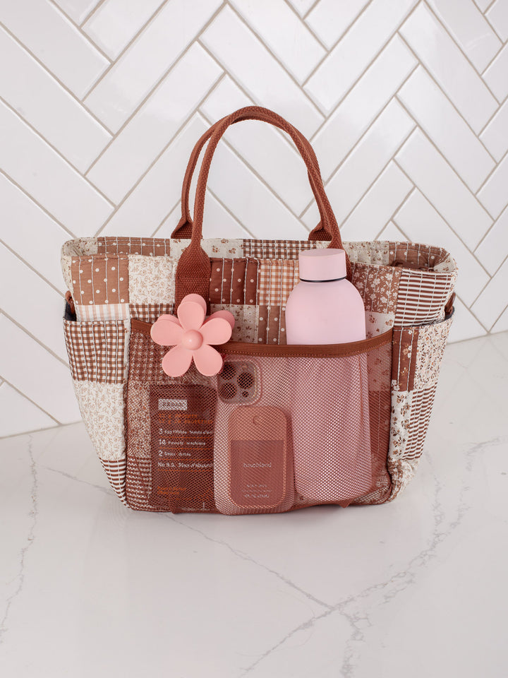 Poppy & Peonies The Lunch Club Lunch Bag in Brown Patchwork with exterior pockets holding a water bottle and accessories.