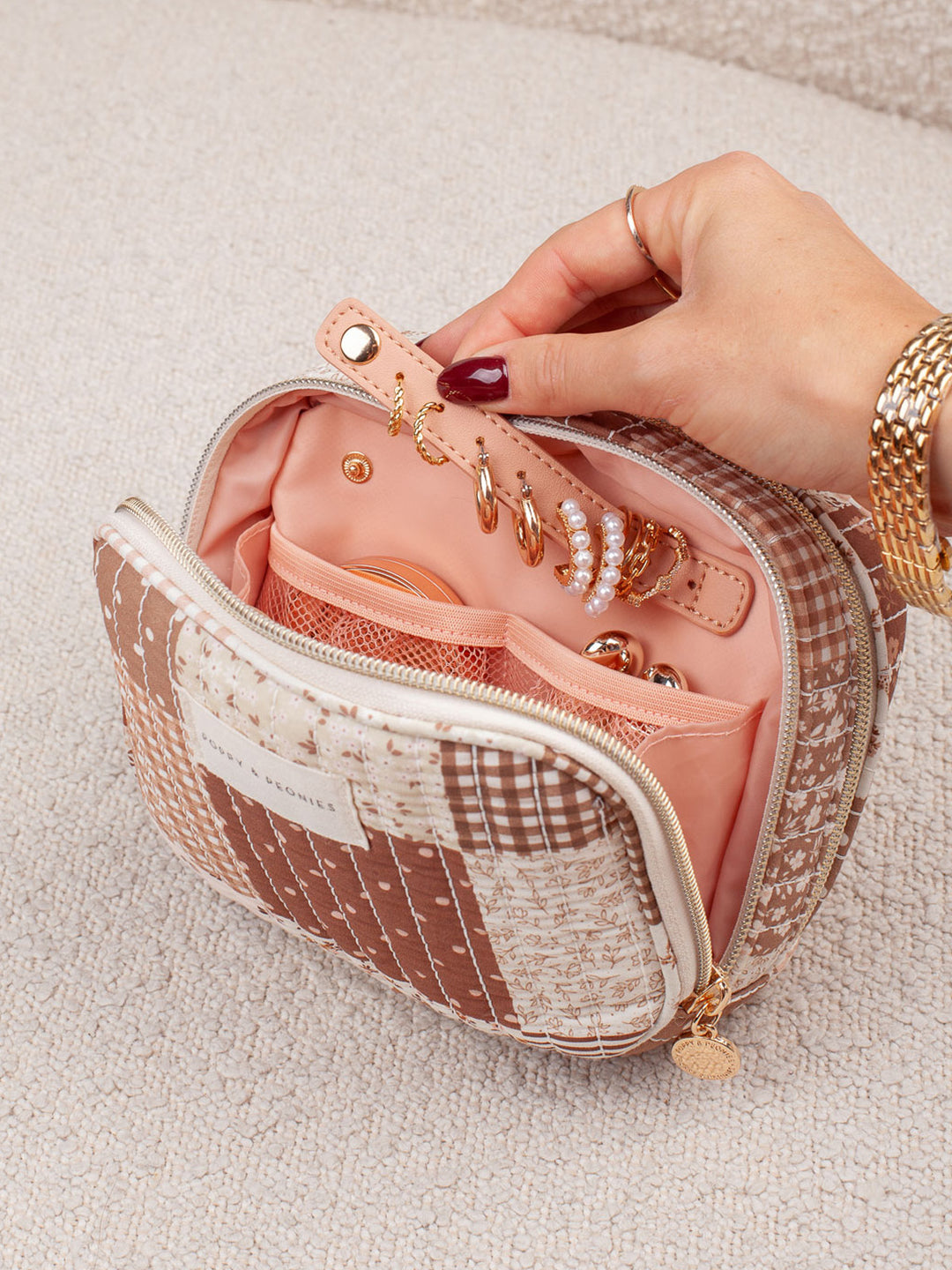 Poppy & Peonies Pretty Connected Case in Brown Patchwork held in hand, showcasing its warm floral print, quilted finish and compact travel-friendly design.