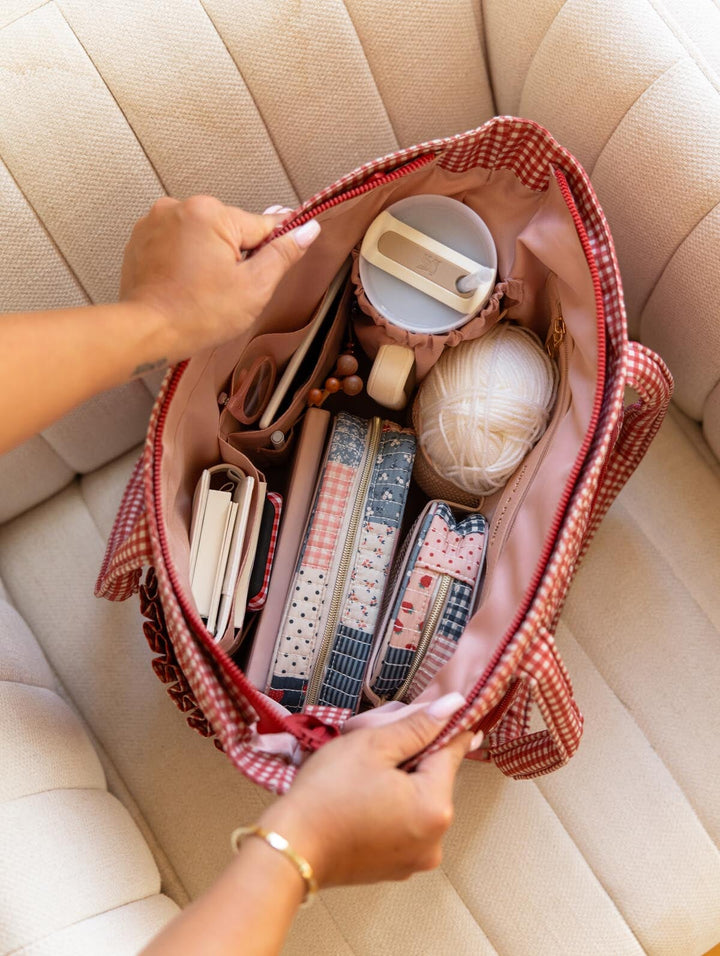 Poppy & Peonies Analog Tote in Heart Berry Gingham open top view, packed with craft and everyday essentials including yarn, organizational cases, notebooks and a travel mug.